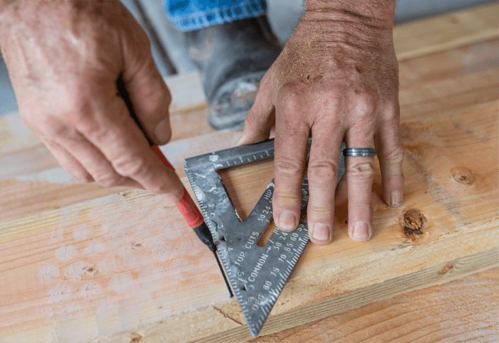 Craftswoman making marks on wooden detail