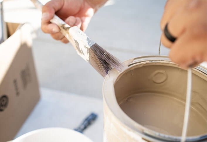 Man holding paint brush and paint bucket